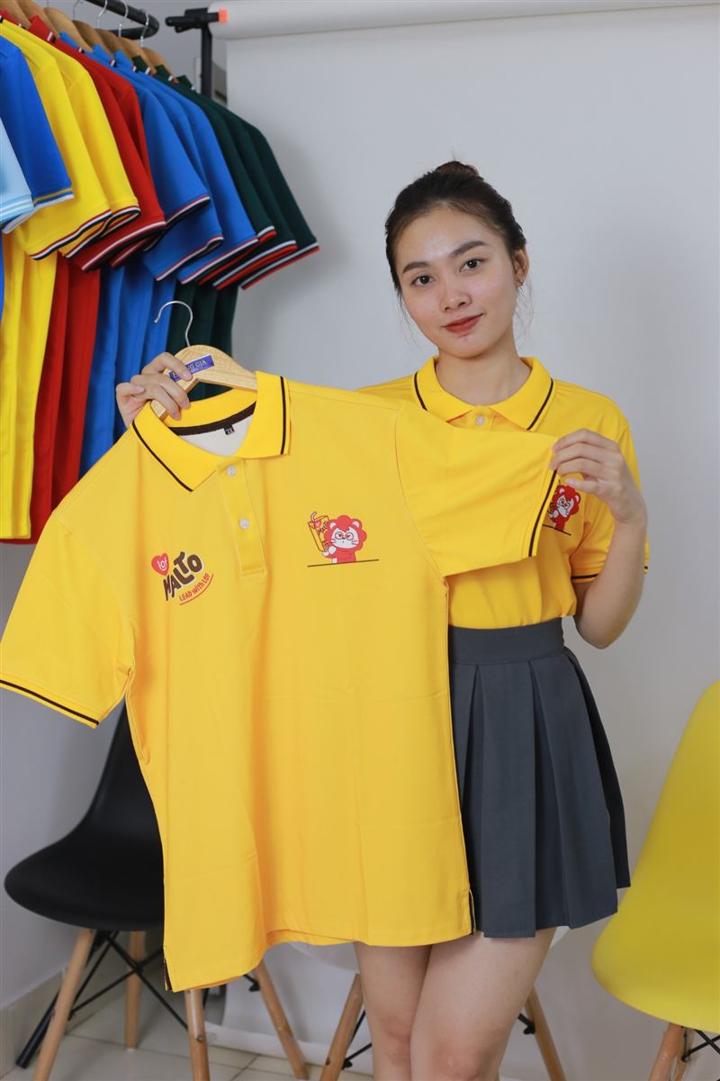 Áo polo vàng in logo treo trên móc gỗ Hoàng Gia